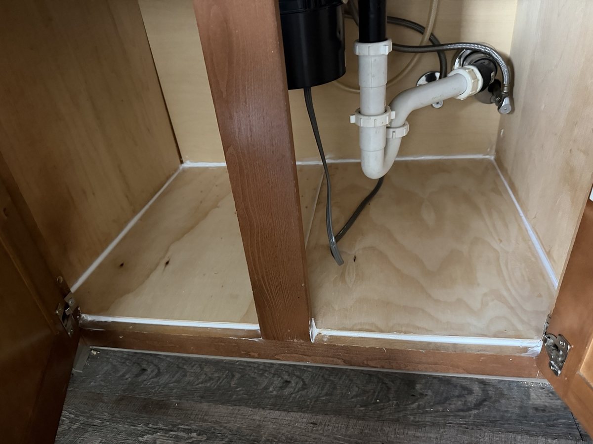 The same under-sink kitchen cabinet after fitting a new plywood base and sealing its edges.