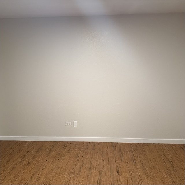 The same apartment living-room wall after painting, with an even finish.